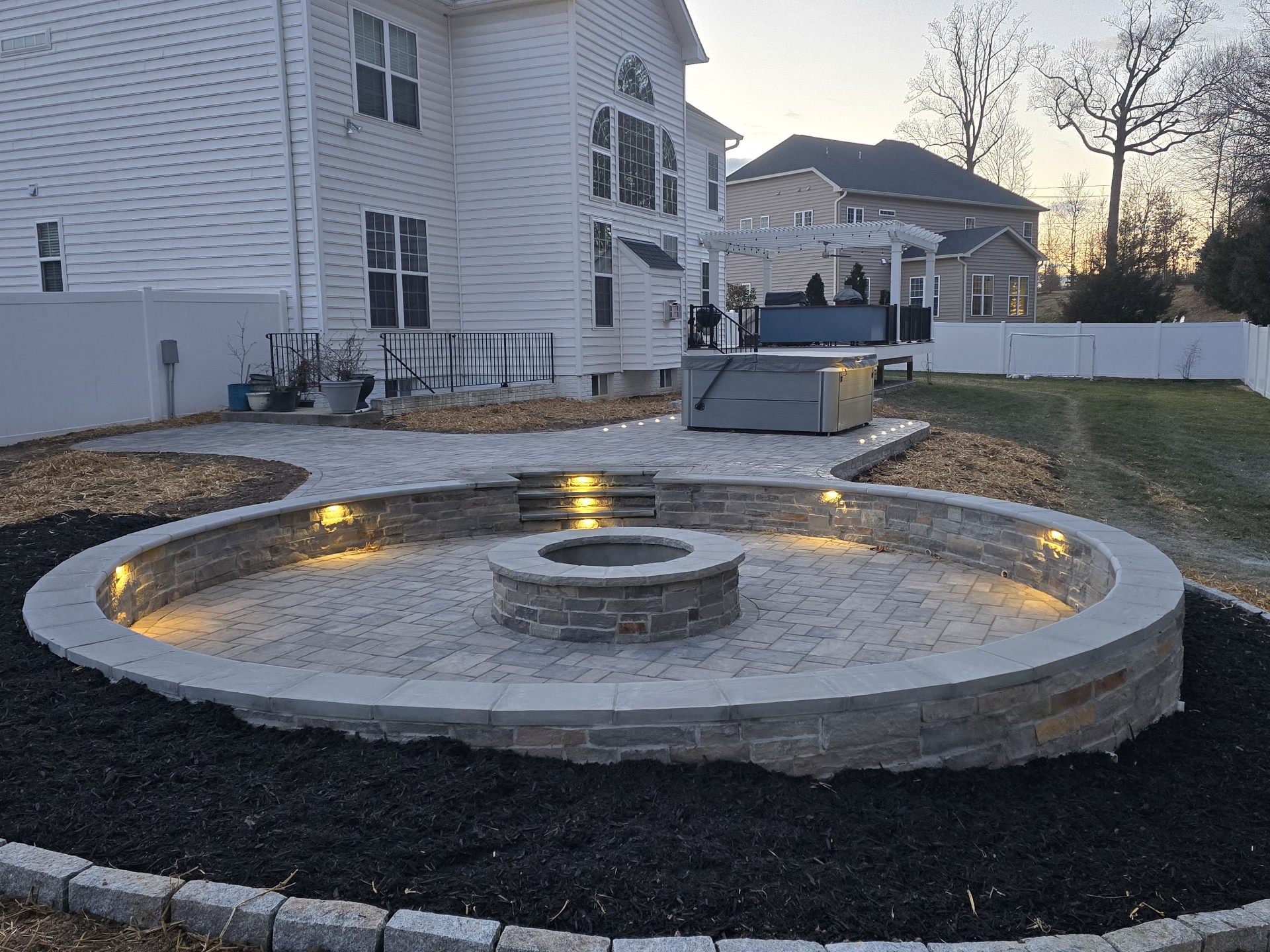 Finished circular fire pit patio with ambient lighting at dusk