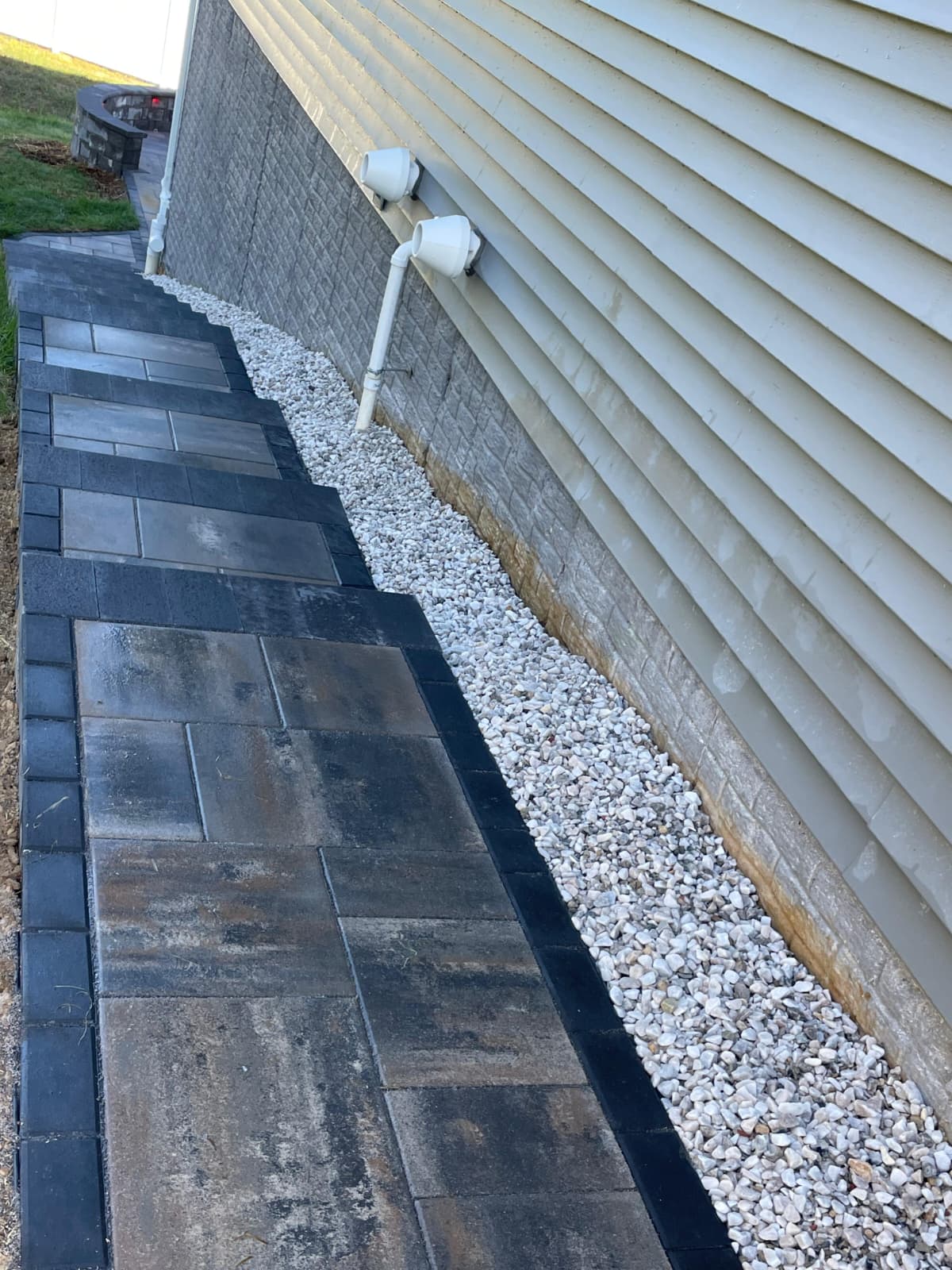 Paver walkway with white river rock drainage along home
