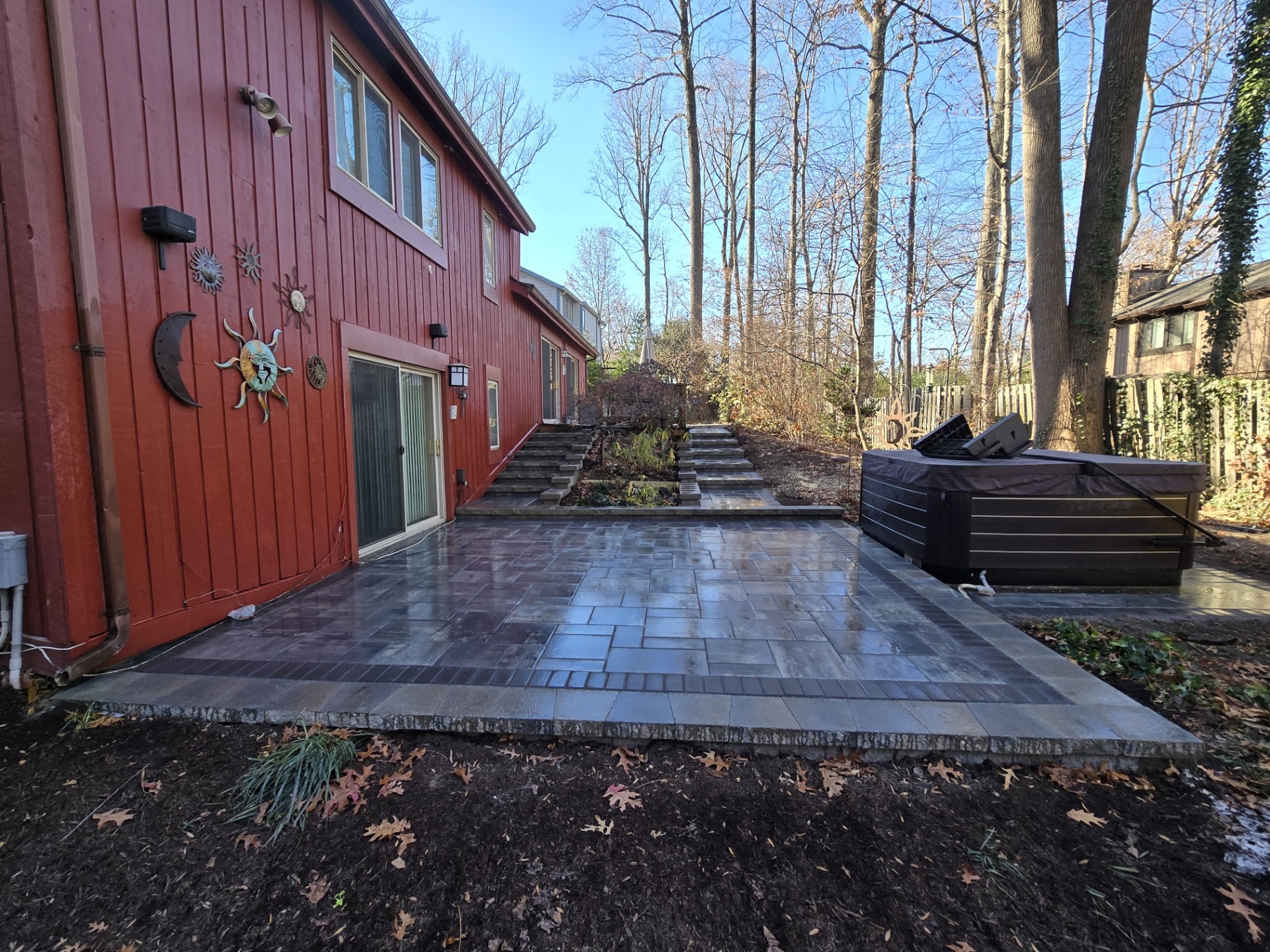 Backyard paver patio with hot tub by the woods